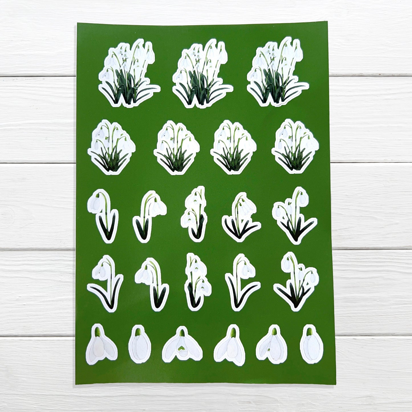 A sheet of A5 size white snowdrop flower stickers on a green background, suitable for decorating planners, diaries, and scrapbooks.