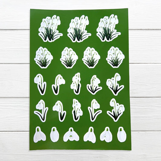 A sheet of A5 size white snowdrop flower stickers on a green background, suitable for decorating planners, diaries, and scrapbooks.