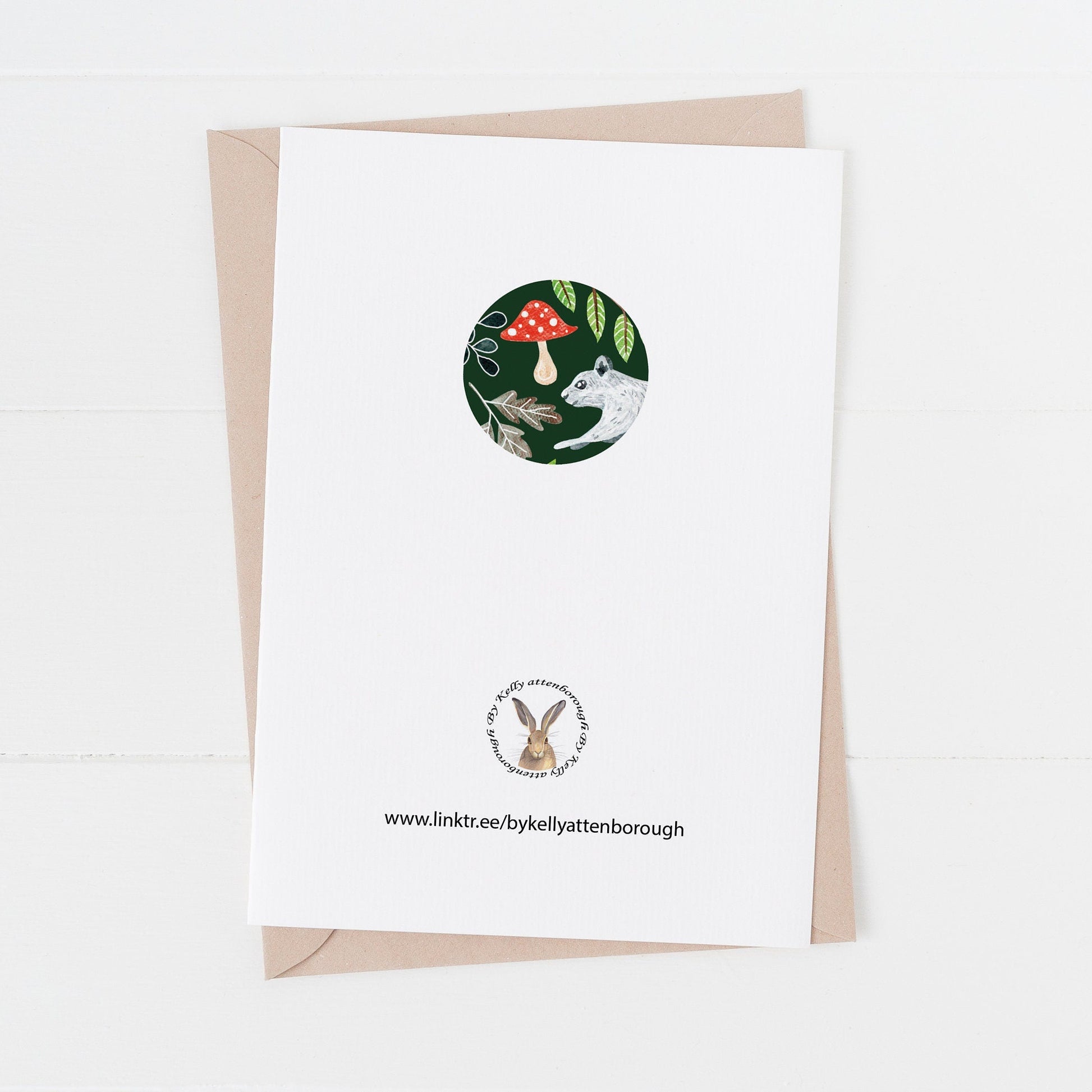 Squirrel & Rabbit Christmas Card back showing a logo and illustration in a circle. laying on a white background.