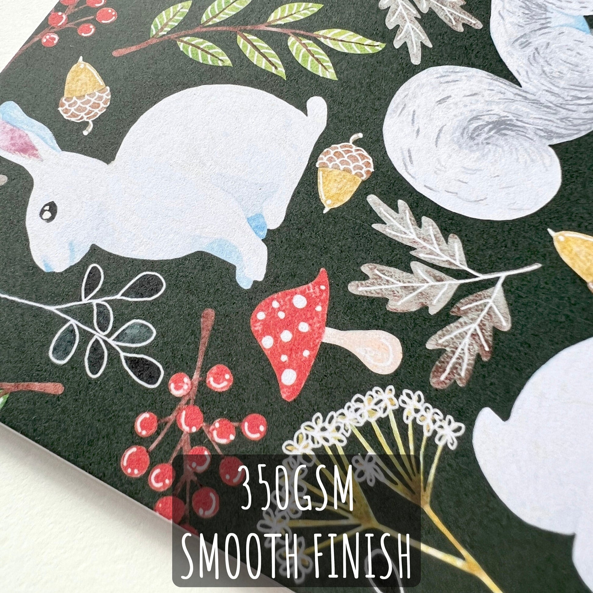 A close up of the Squirrel & Rabbit Christmas Card showing the details and textures of the illustration and paper stock. with the text: 350gsm smooth finish.