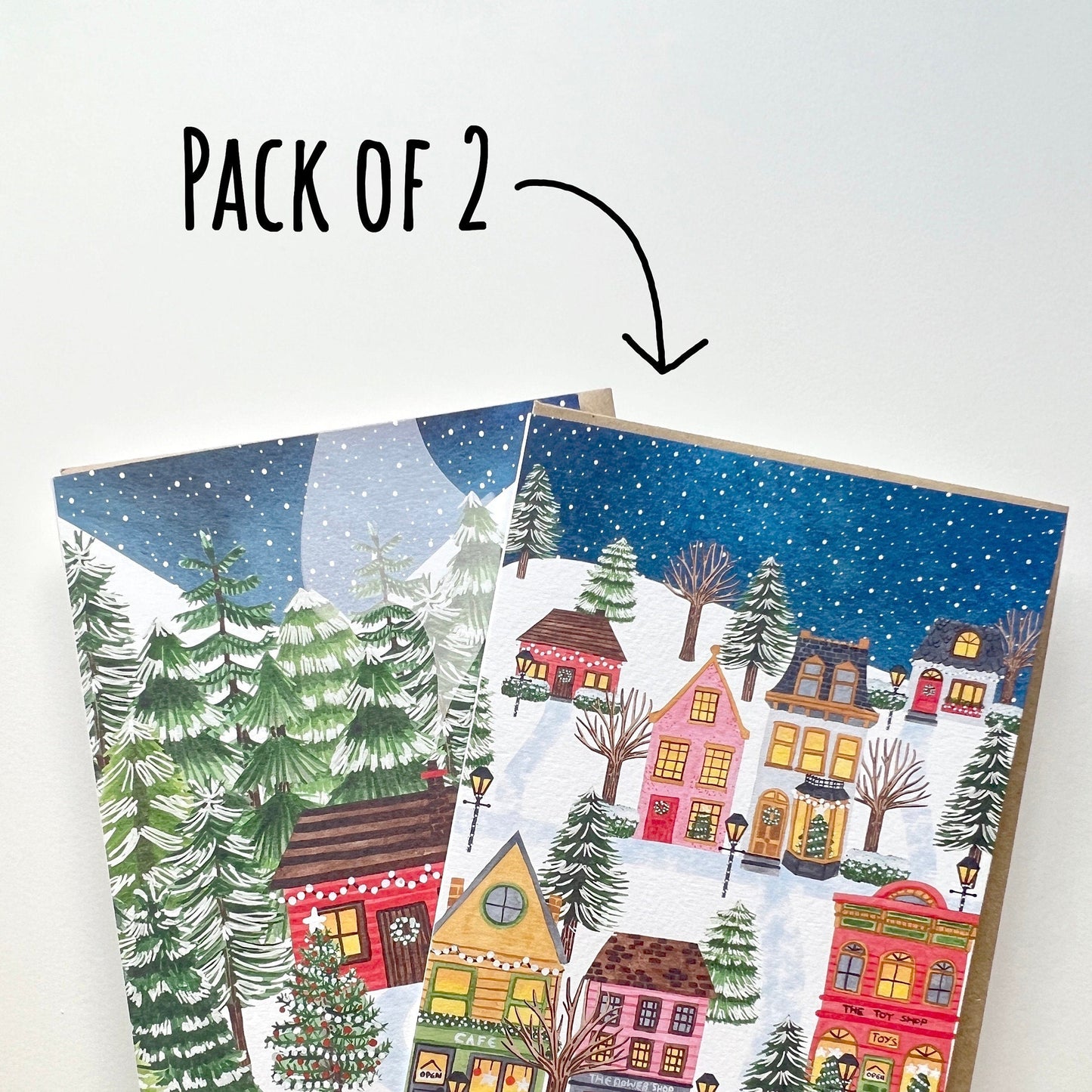 Two Christmas-themed greeting cards held by a hand with text 'Pack of 2'. with a white background.