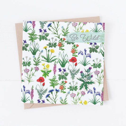 A floral birthday card featuring a variety of wildflowers with a 'Be Wild' text at the top right corner, accompanied by a kraft paper envelope.
