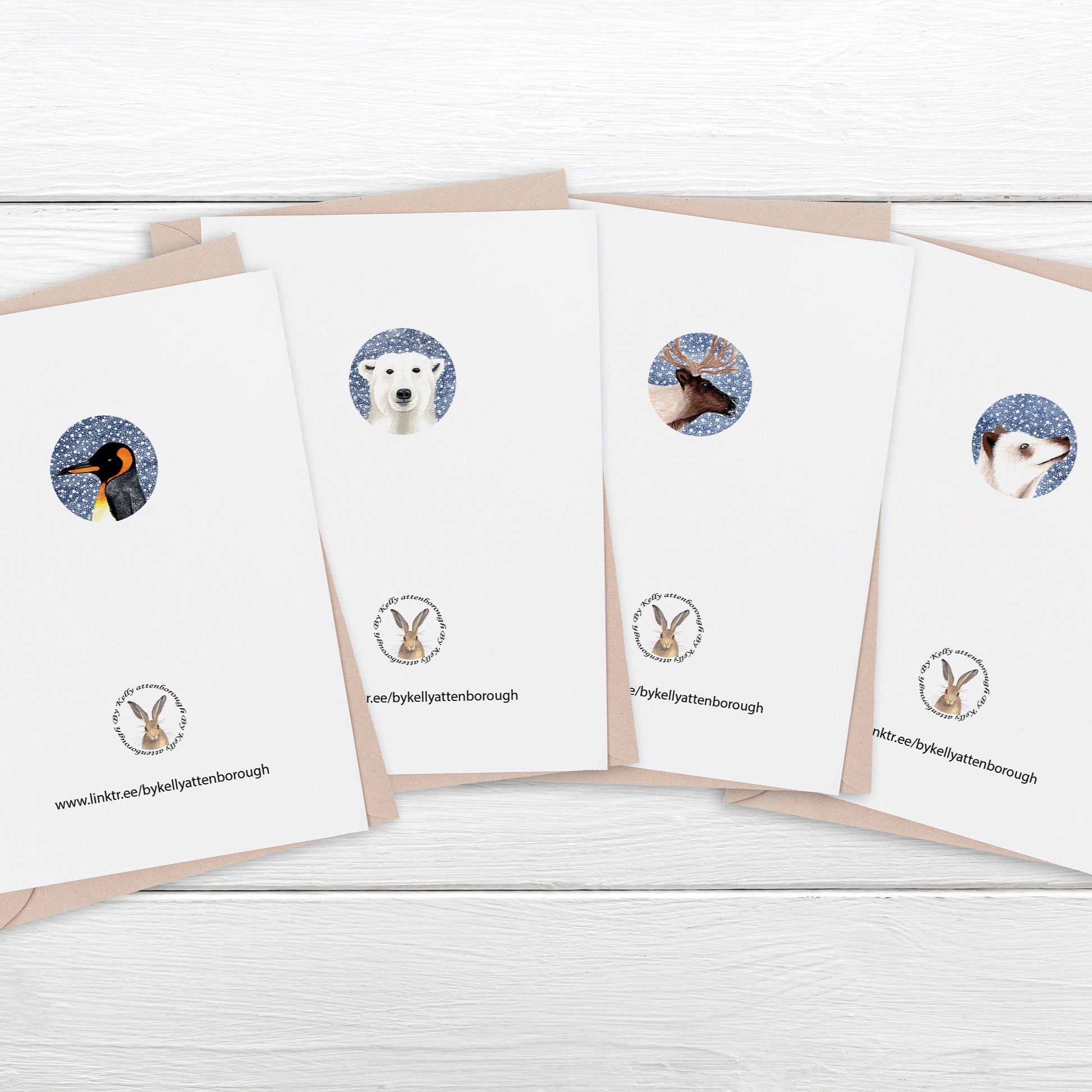Showing the back of a set of greeting cards with animal illustrations laying on a white wooden surface.