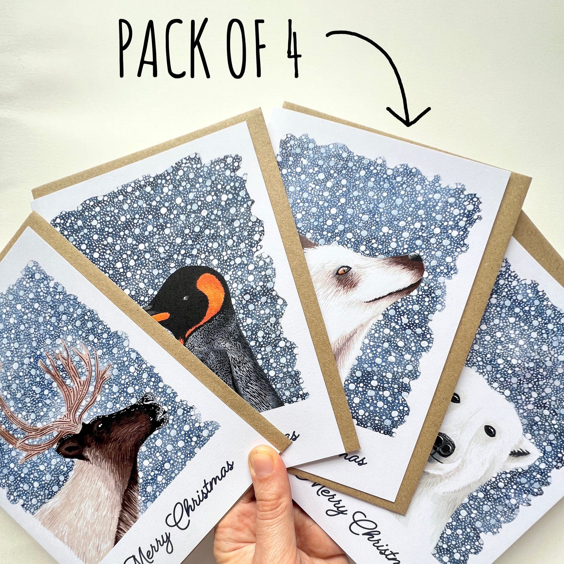 Pack of four Christmas cards with animal illustrations held by a hand. with text Pack of 4