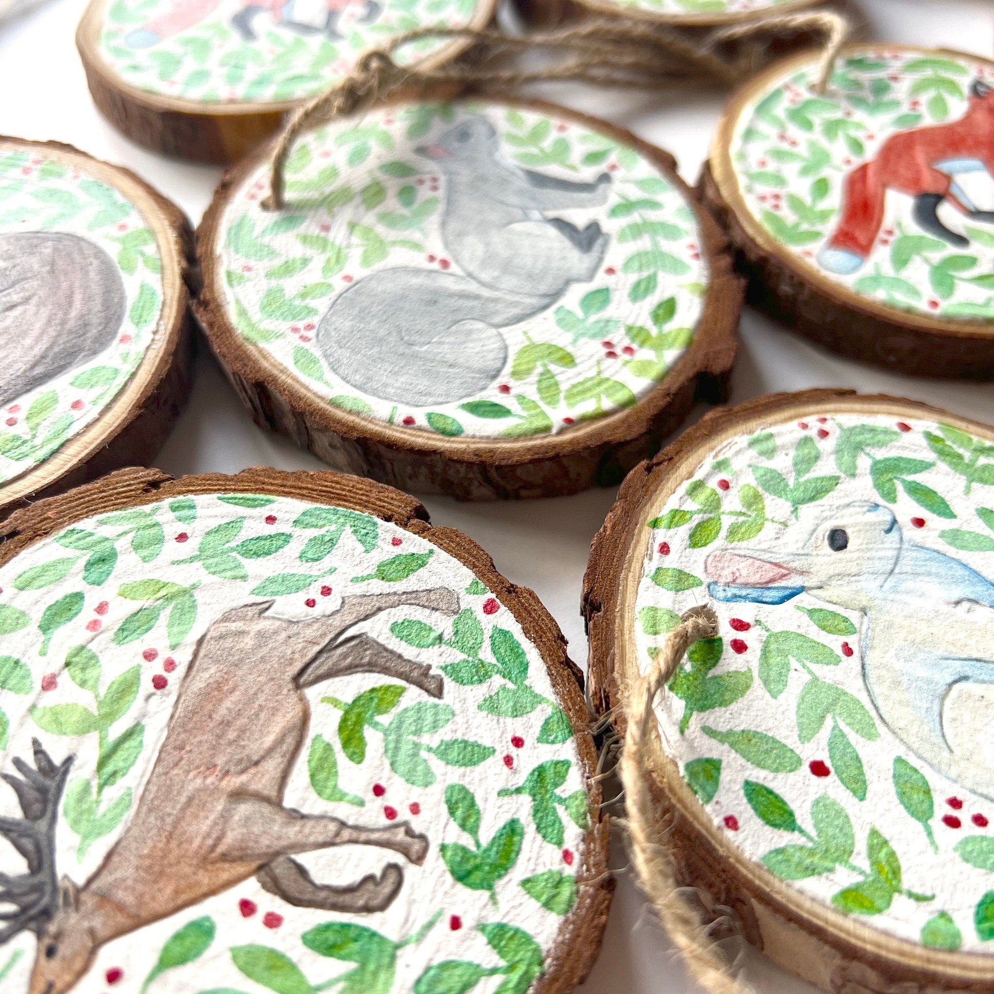 Wooden ornaments close up showing the details of the animal illustrations. laying flat on a white background.