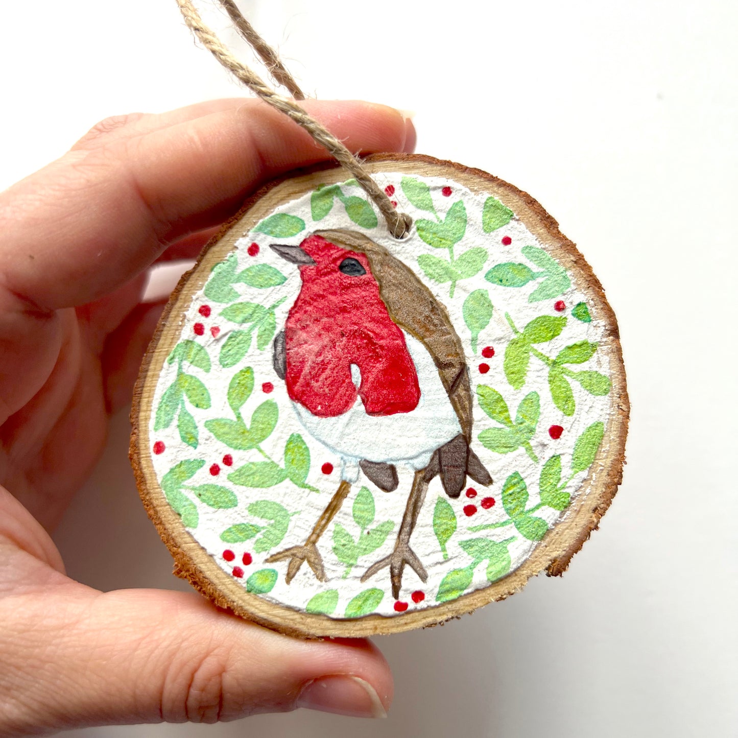 Hand-painted wooden slice Christmas decorations featuring various woodland animal designs including a fox, bear, deer, robin, rabbit, and squirrel, surrounded by green and red painted foliage.