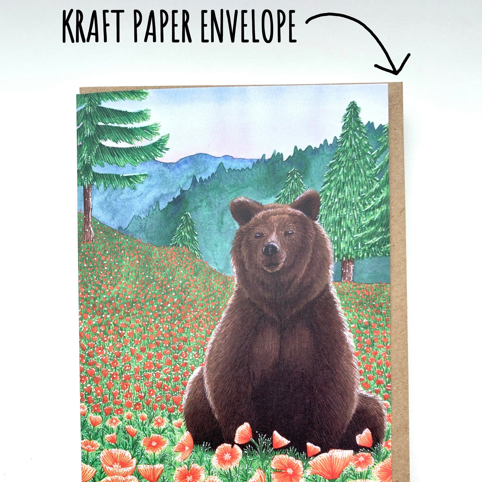 Greeting card with a bear in a field of flowers held by a hand, with 'Kraft Paper Envelope' text above.