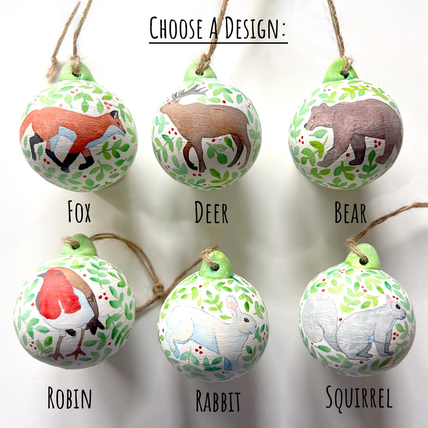 Woodland Animals Ceramic Baubles showing six on a white background. a fox, a deer, a bear, a robin, a rabbit and a squirrel one of each design shown.