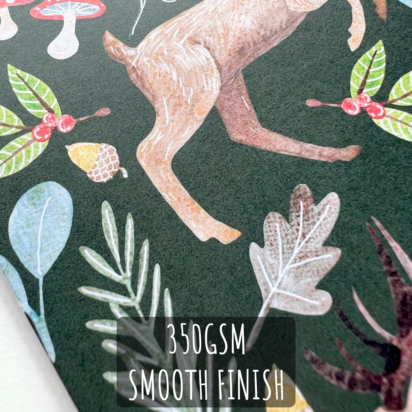 Woodland Stag and Doe Deer Christmas Card close up showing the details and textures of t he illustration and paper stock. with text 350gsm smooth finish.