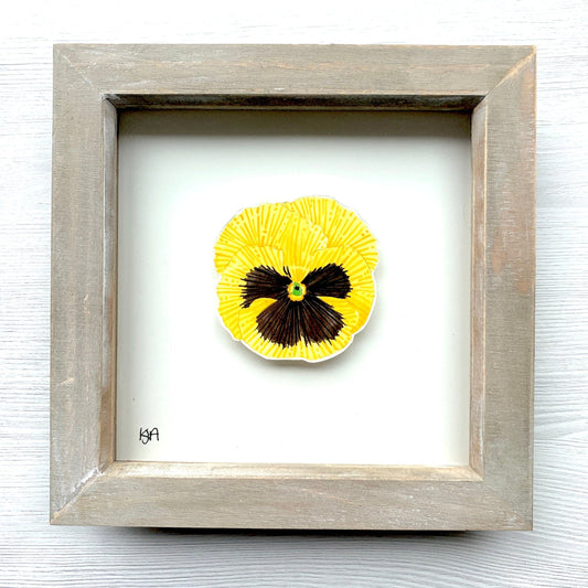Hand painted vibrant yellow and black pansy flower on a piece of paper, with the artwork placed in a rustic washed effect wooden frame.