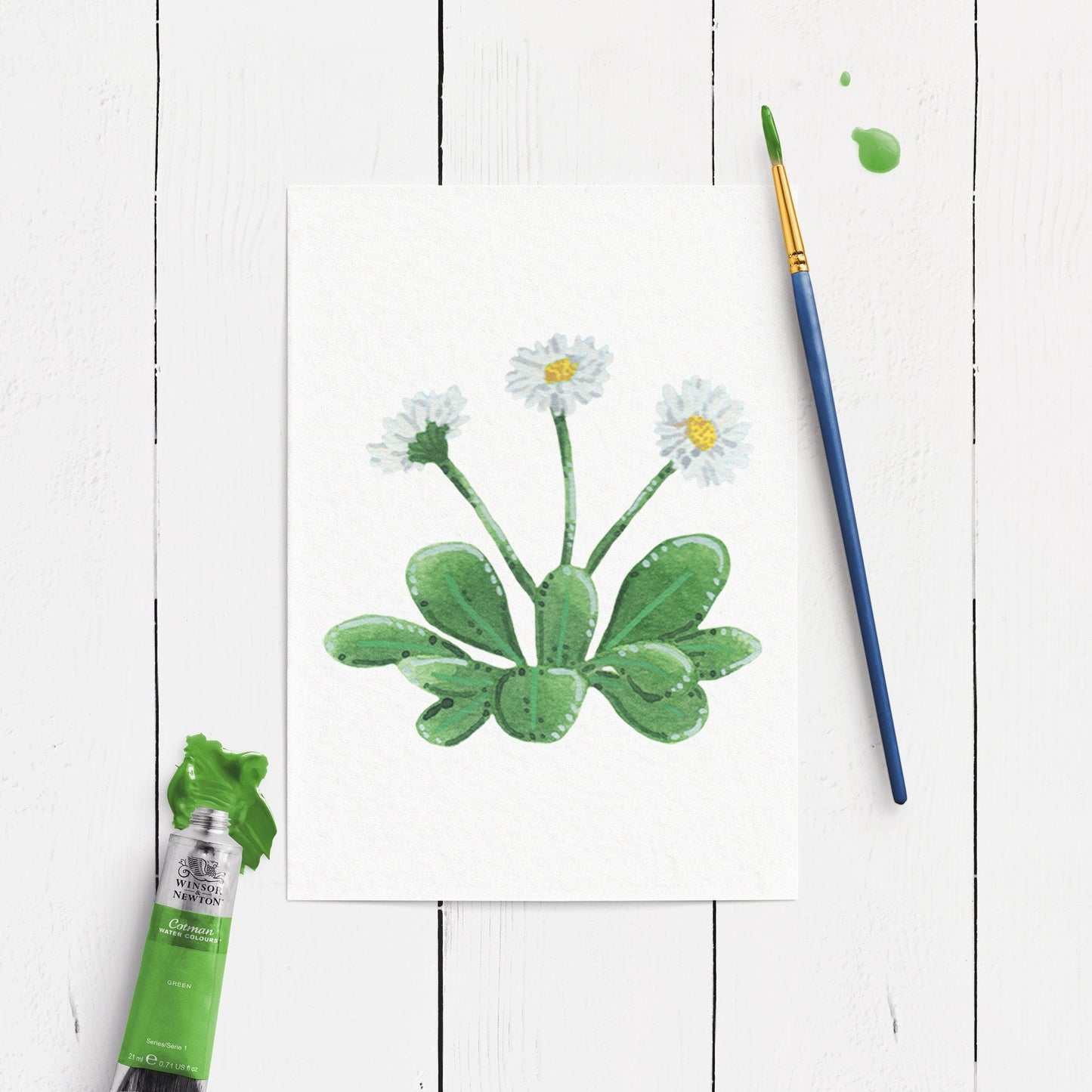 Unframed daisy flower artwork in watercolour and gouache. shown on a white wooden surface.