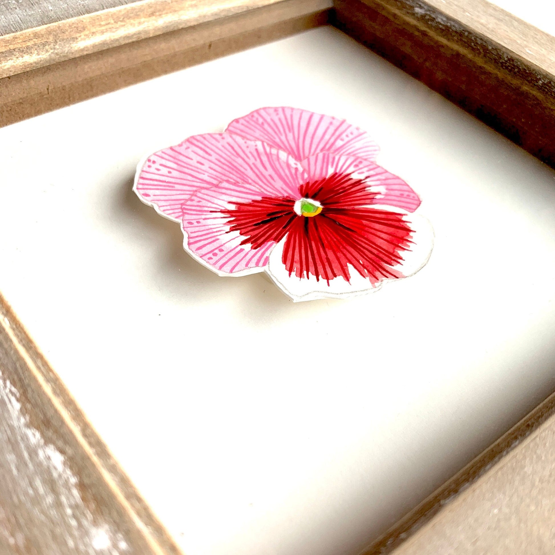 Framed pansy flower watercolour and gouache painting in pink, red, and white. showing a close up of the line details and paint textures.