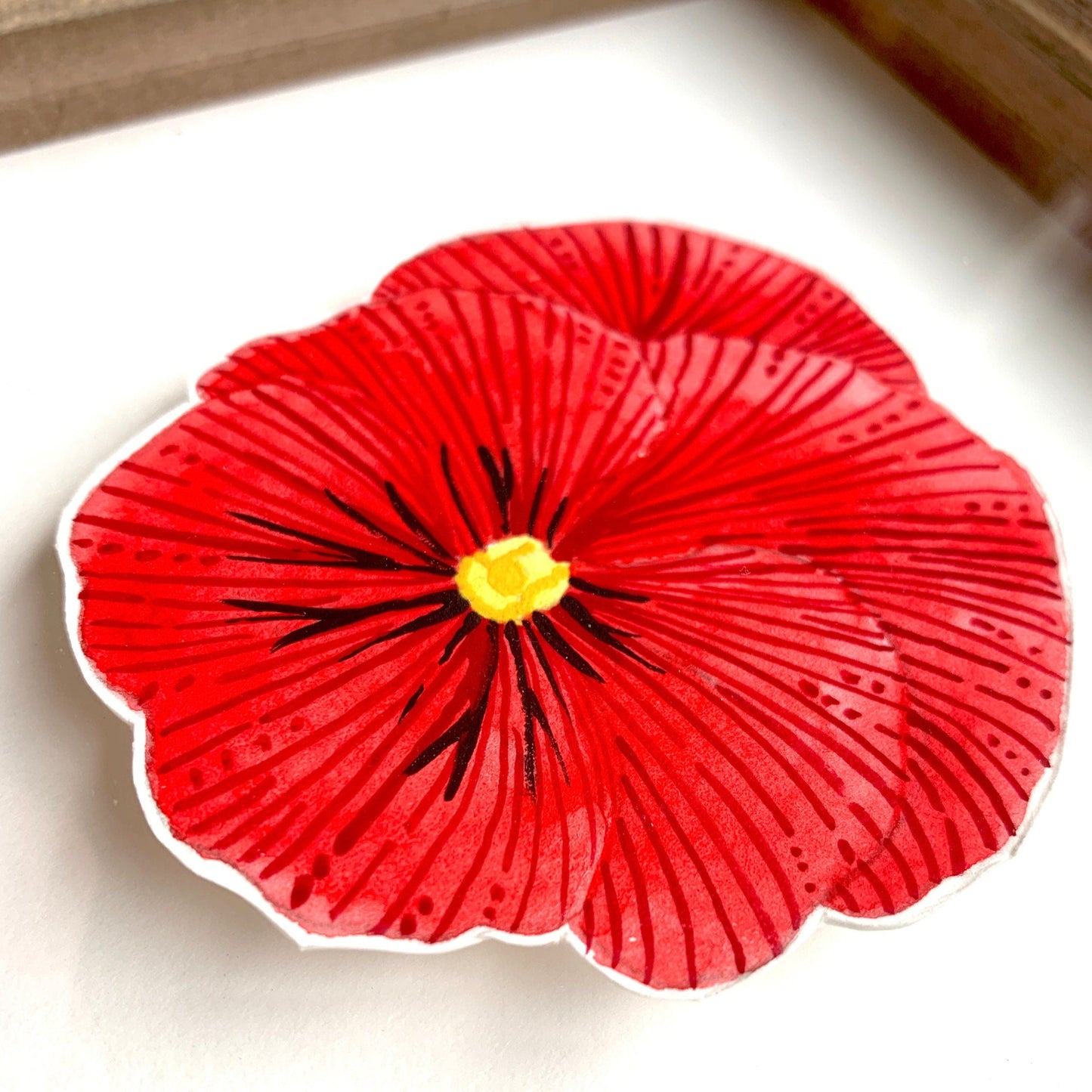 A close up of a red pansy flower painting showing the line details and paint textures