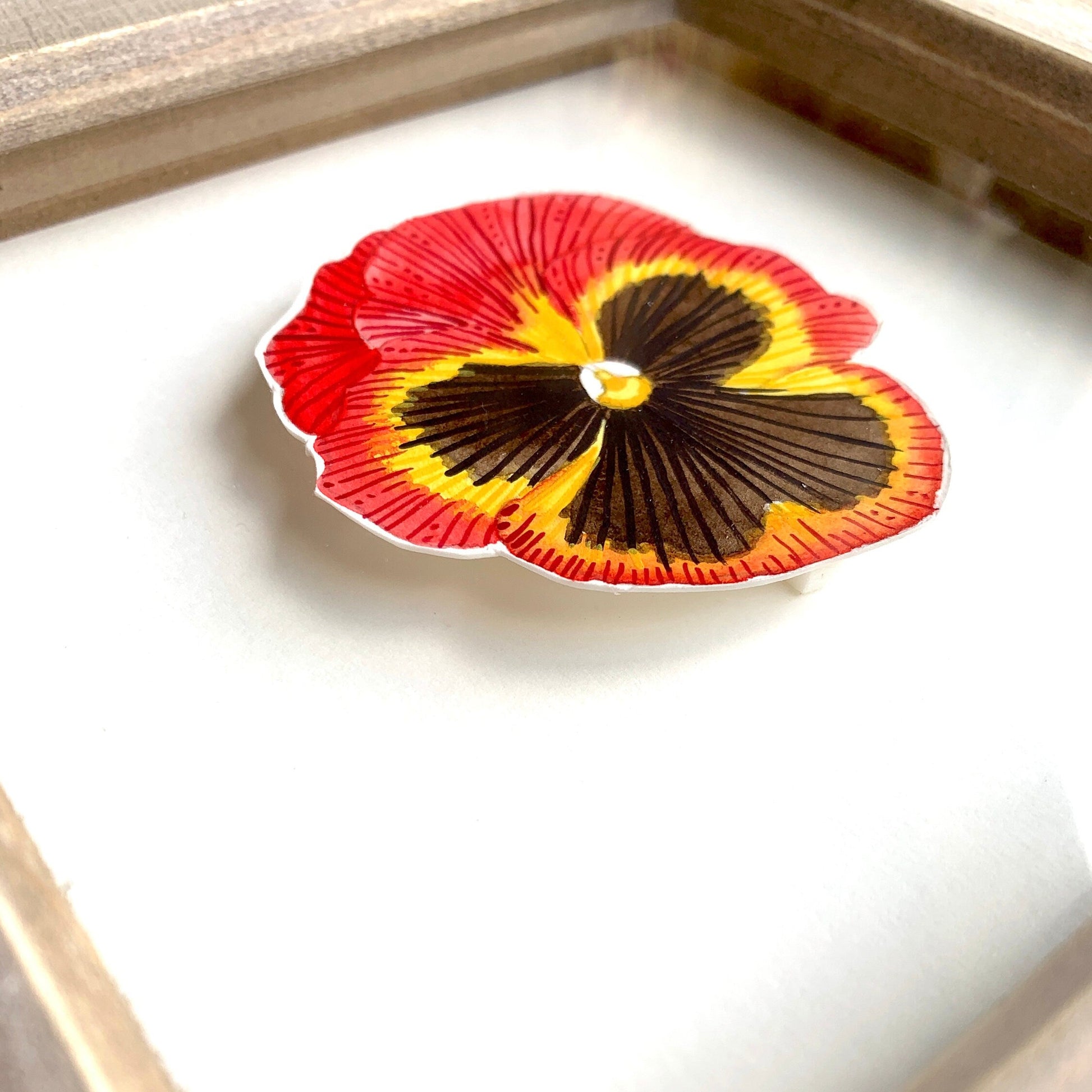 Red yellow and black pansy flower painting in rustic frame close up. showing the details of the painting and frame.